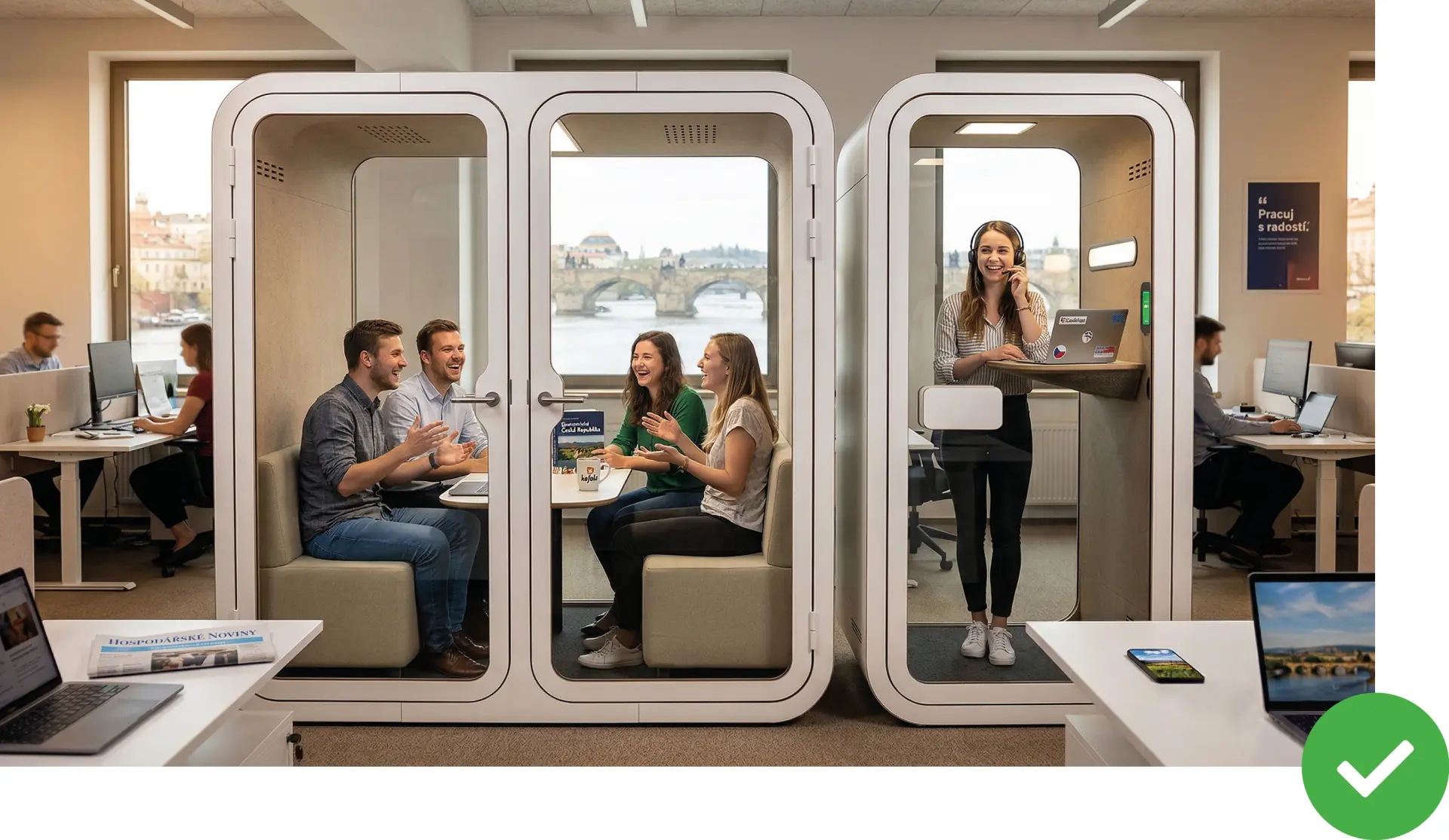 Fotka tiché a uklizené kanceláře s bílými akustickými boxy Acoustic Space a lidmi soustředěně pracujícími nebo konverzujícími v nich, s výhledem na Karlův most.